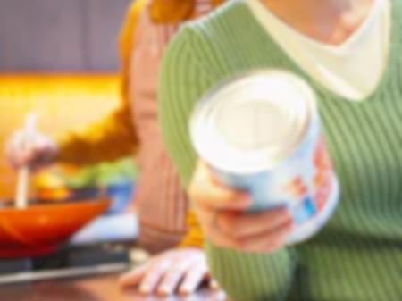 Woman inspecting canned food in kitchen