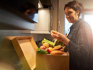 Mujer abriendo una caja con un kit de alimentos