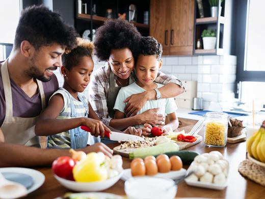 Familia feliz en la cocina, divirtiéndose mientras cocinan un plato saludable juntos.